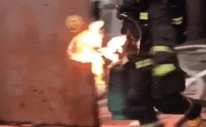 消防员手提燃烧的煤气罐扔进水里